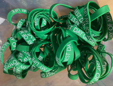 pile of green wristbands with best day of my life written in white